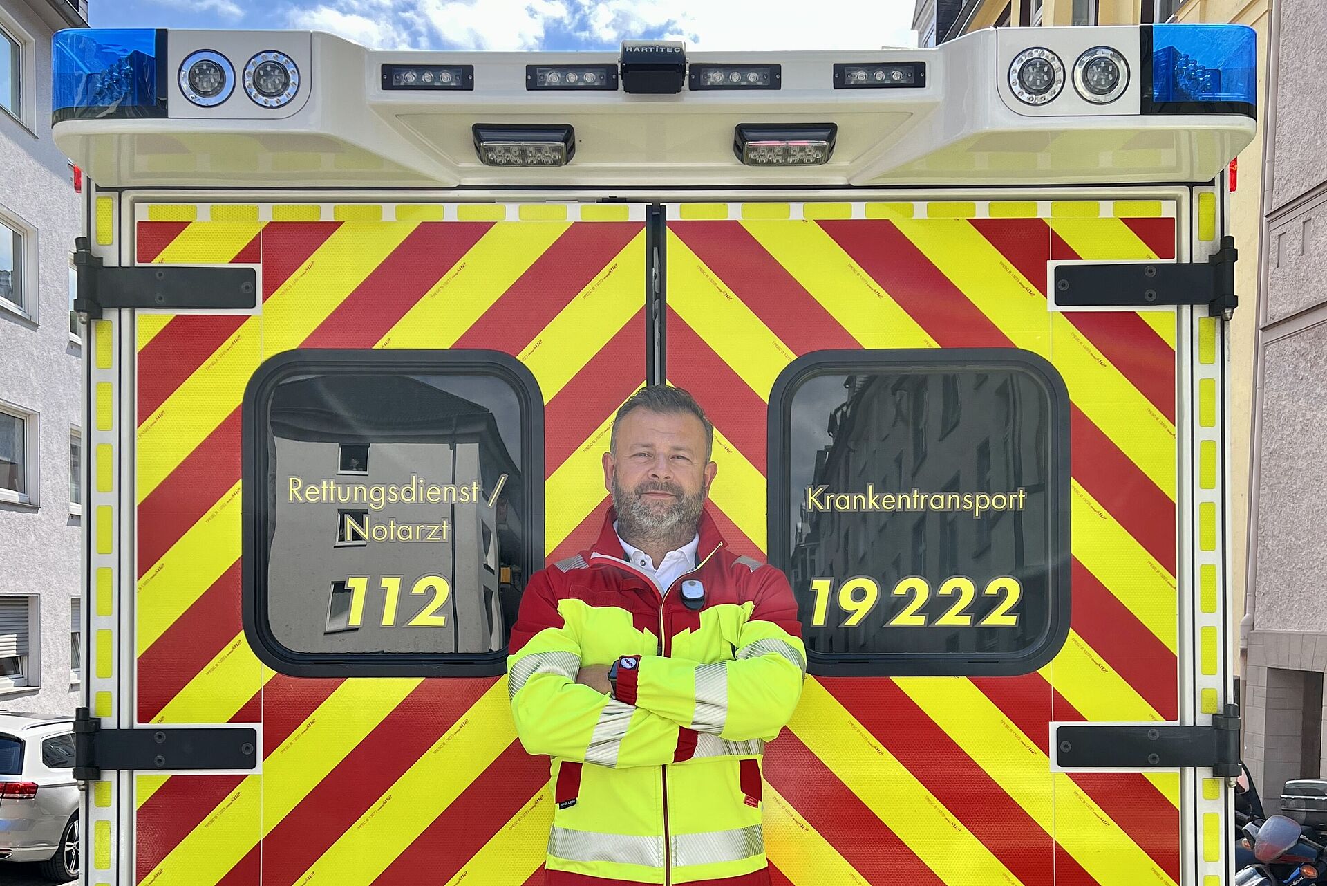 Claudio - RTW Rettungsdienstmitarbeiter in Dienstkleidung steht vor RTW